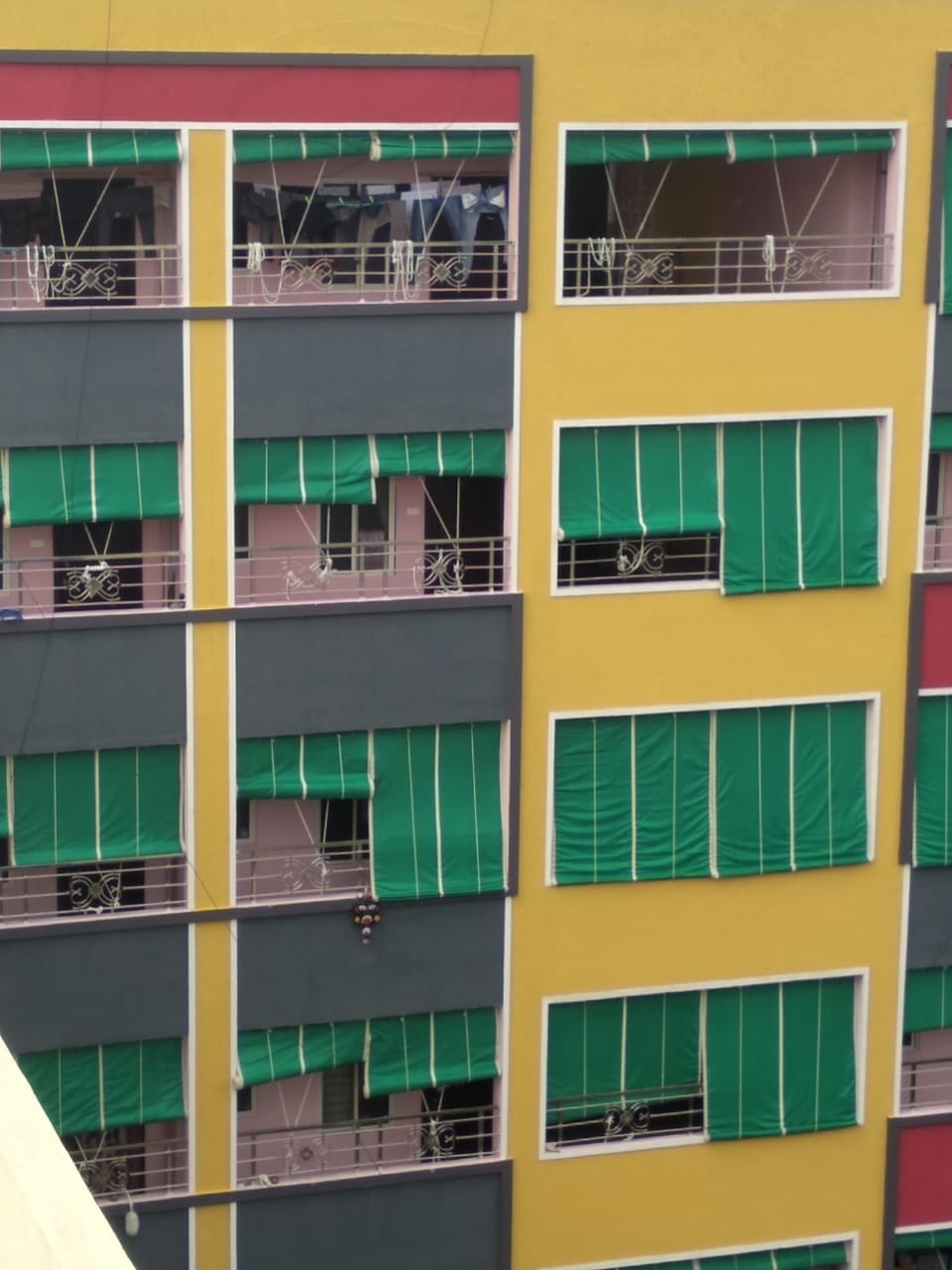 Green balcony blinds and shade nets across a colourful apartment building